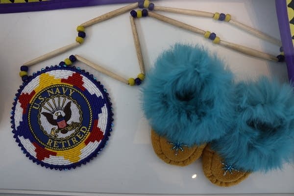 Overhead shot of a handmade U.S. Navy logo next to a pair of children's boots with bright blue fur.