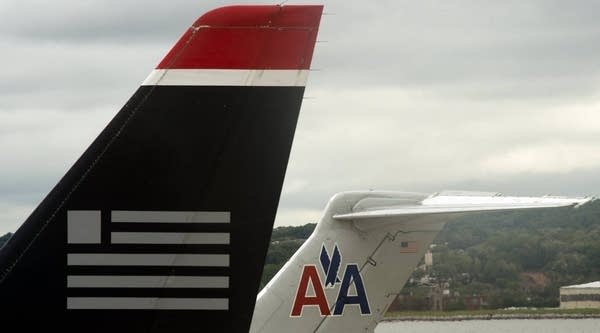 A US Airways tail rest on the tarmac near an American Airlines plane at Ronald Reagan Washington National Airport in Arlington, Va. US Airways has won the support of unions at the bankrupt American Airlines for a proposal to fold the two companies into one giant carrier, US Airways CEO Doug Parker said on April 20, 2012.