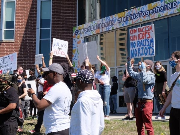 a crowd holds protest signs 