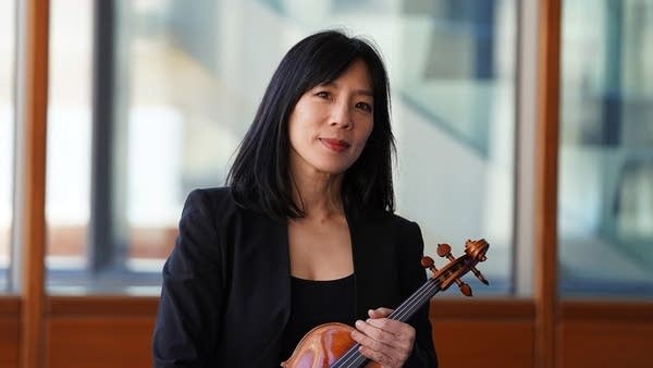 A woman poses for a portrait while holding a violin