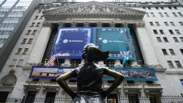 The Fearless Girl sculpture in front of banners for the newly-formed and independent General Electric companies at the New York Stock Exchange on Tuesday.