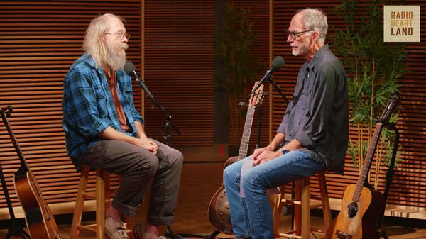 Two men have a conversation in a recording studio