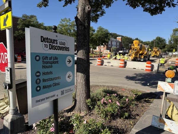 A sign shows how to navigate road construction on foot.