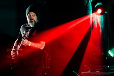 A musician plays cigar-box guitar onstage
