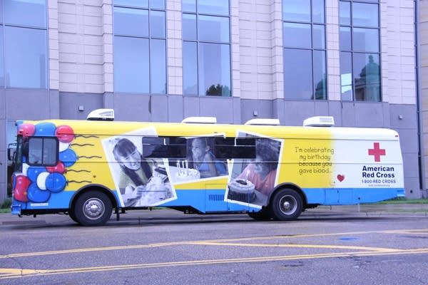 A yellow and blue bus with a Red Cross logo. 