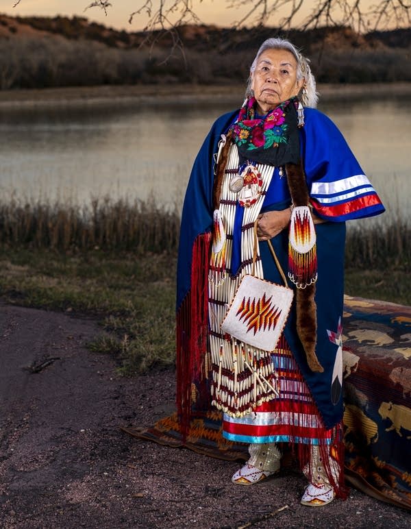 A woman stands near a body of water.