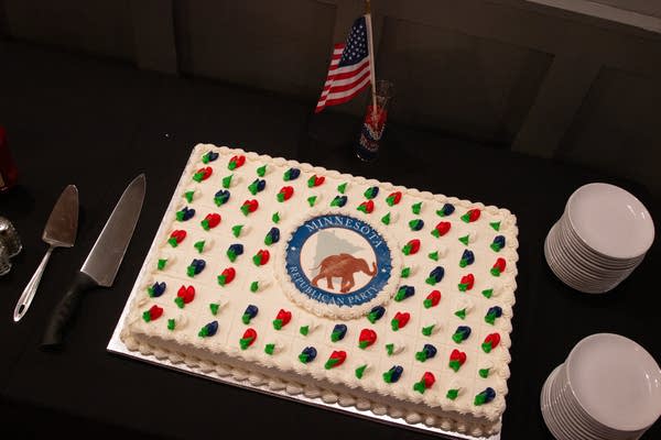 A sheet cake with the Minnesota Republican Party seal sits on a black table.