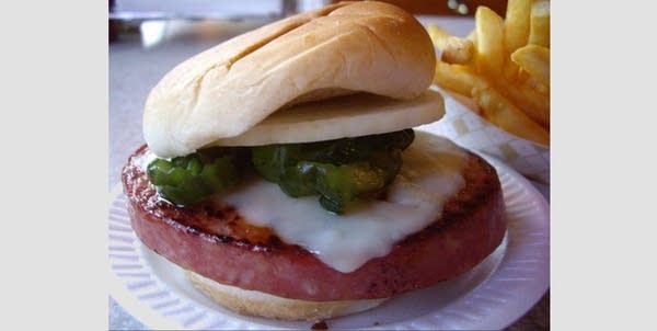 Thick-cut fried bologna sandwich on a white bun w/ pickles, cheese, onions