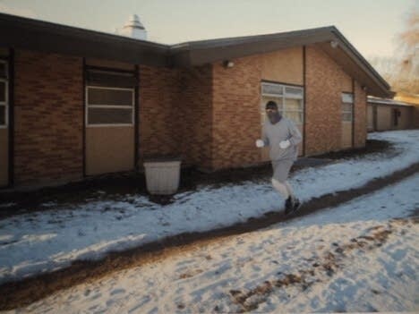 A man runs in the winter around a building.