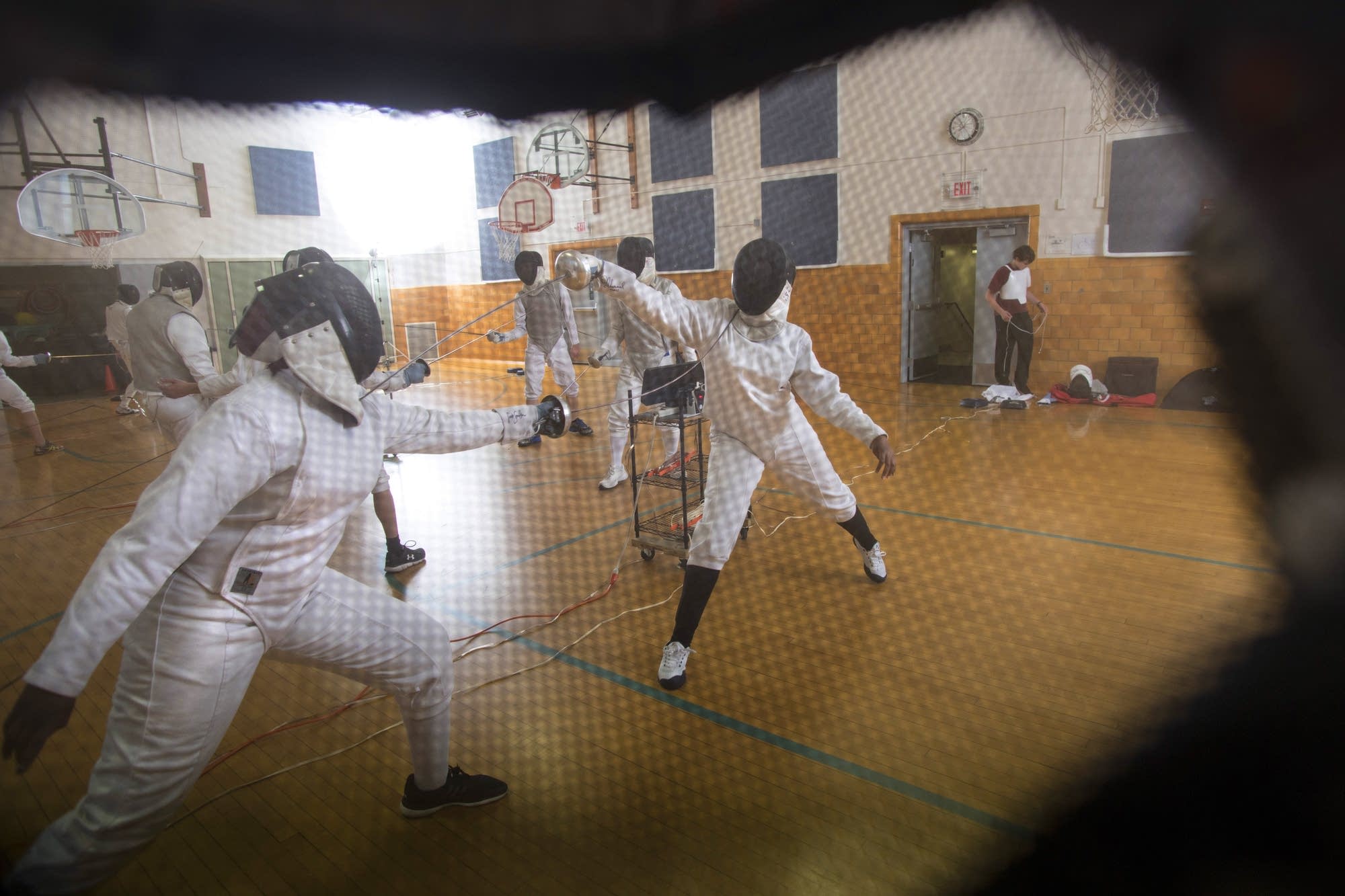The STEM Academy girls team practices, seen through a fencer's mask.