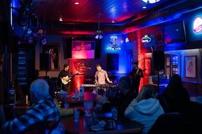 Three men performing on stage and crowd watching