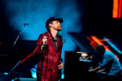 A musician sings onstage in a large arena