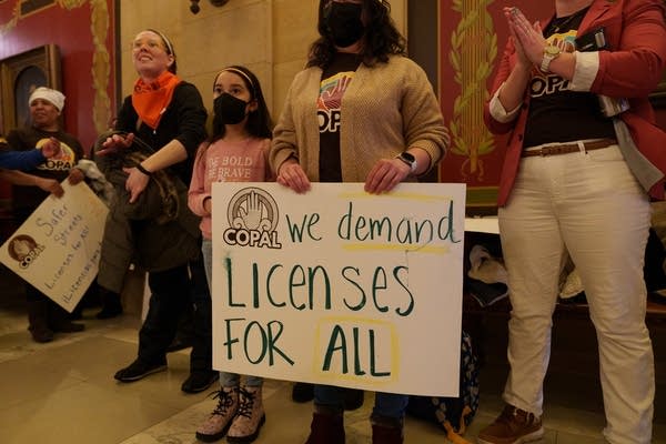 People hold signs and wear masks