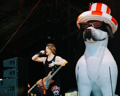 A musician sings and plays guitar on a large outdoor stage