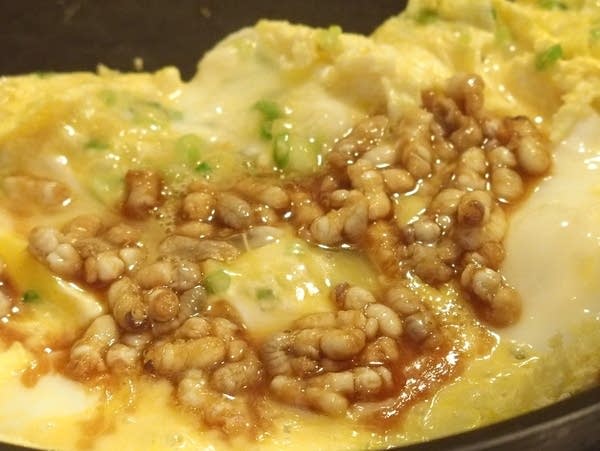 A handful of bee larvae marinated in sake and soy sauce in an omelet