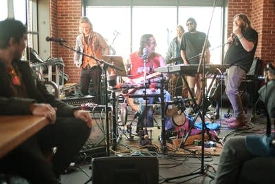 A musician plays several instruments simultaneously in a taproom