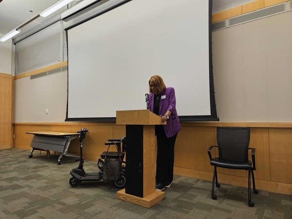 A woman presents at a podium.