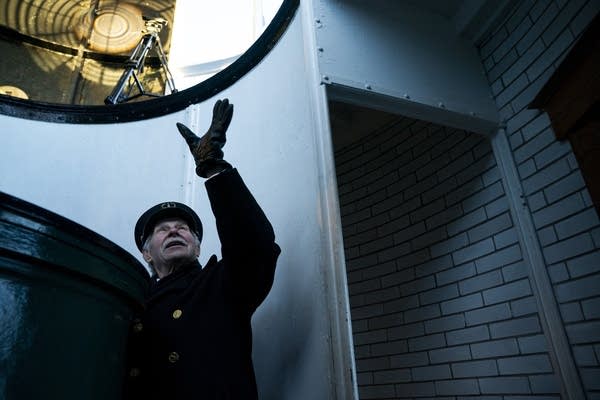 A man points up to the interior of a lighthouse.