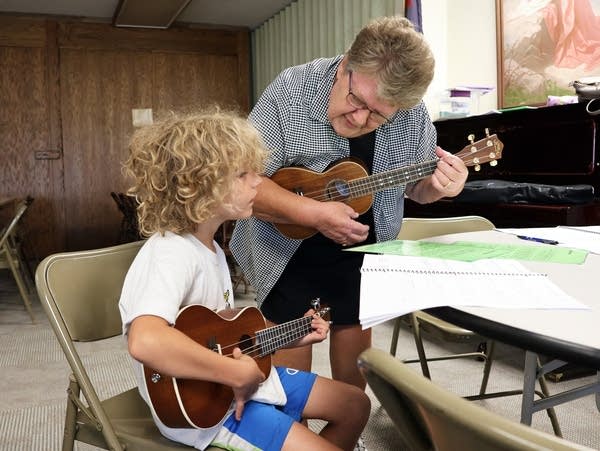 a woman and a young boy play stringed instruments