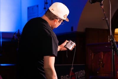Man on stage holding tape player