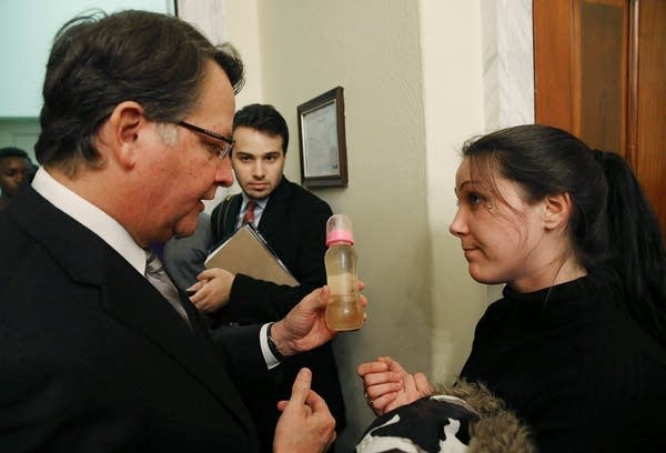 Flint resident Jessica Owens shows Sen. Gary Peters (D-MI) a baby bottle full of contaminated water, during a news conference after attending a House Oversight and Government Reform Committee hearing on the Flint, Michigan water crisis on Capitol Hill February 3, 2016 in Washington, DC. 