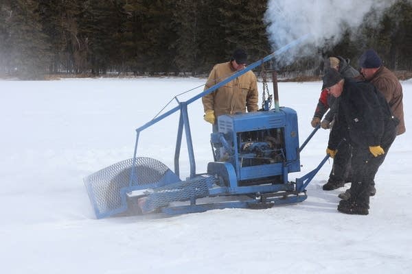 Men use an industrial saw to carve up ice.