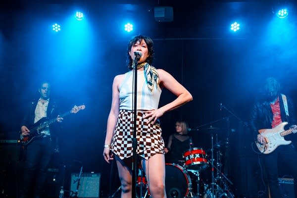 A five-piece band performing onstage in a music venue