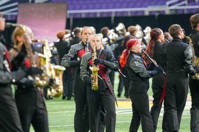 A marching band performs on the field of a football stadium.