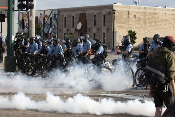 A line of police officers on bicycles in riot gear 