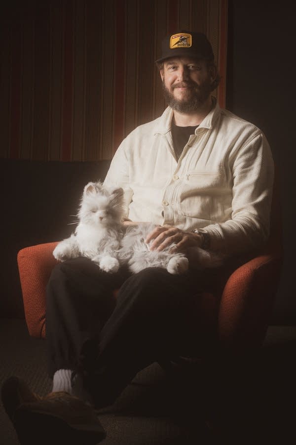 Justin vernon posing for photos with a fake cat