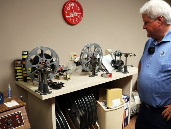 a man looks at reels of film on a table