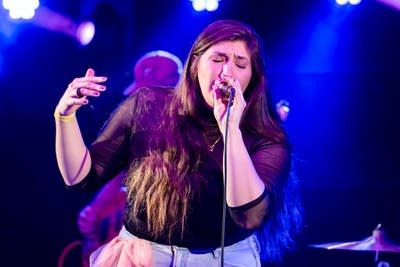 Woman singing into microphone with eyes closed