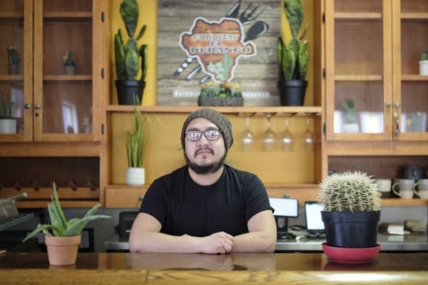 A man poses for a portrait in his restaurant