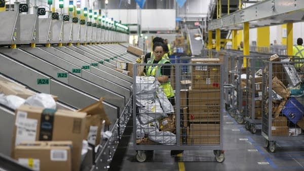 The raises are in line with average national wage growth this year. Above, workers process packages in an Amazon fulfilment center.