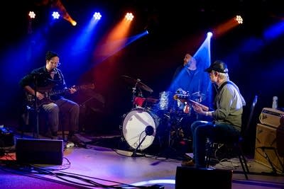 Three musicians performing onstage in a music venue