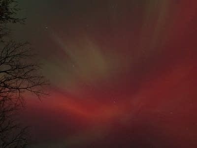 A dark view of green and red lights in the night sky.