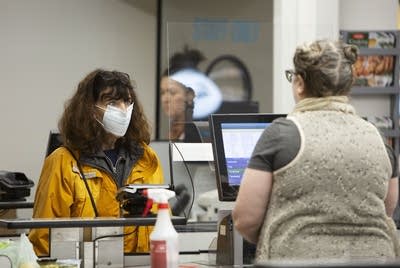 A woman wearing a mask at a checkout sign.