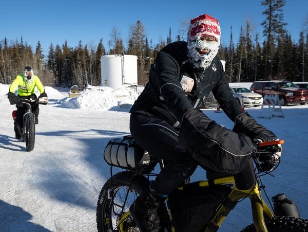 A snow-encrusted biker rides into a gas station