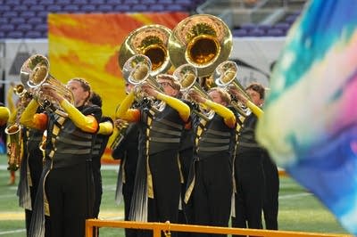 A marching band performs on the field of a football stadium.