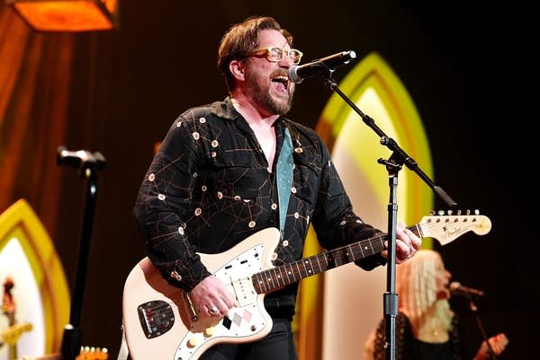 A man sings and plays guitar onstage