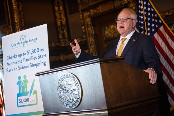 A man gestures with his hand as he speaks at a podium