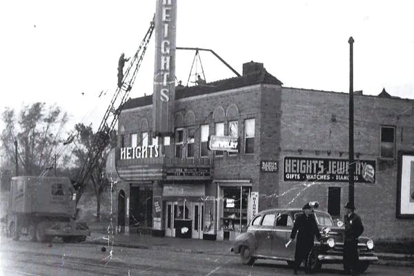 Black-and-white photo of workers installing a sign on a movie theater.