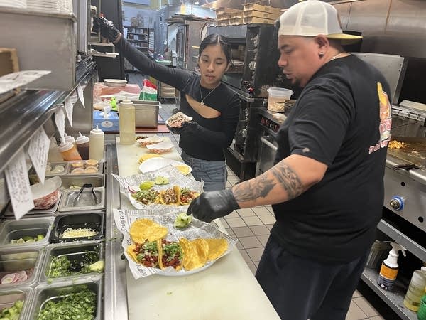 Two people work in a kitchen at a restaurant.