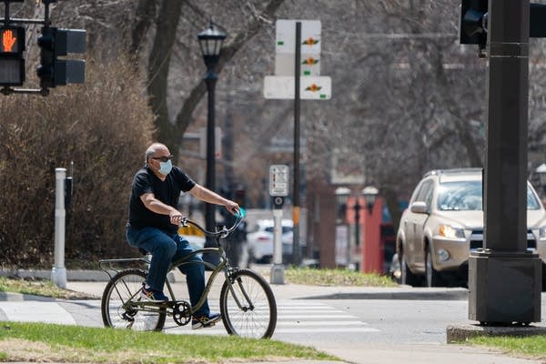 A man bikes with a mask on.