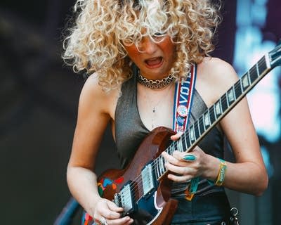 A musician plays guitar on a large outdoor stage