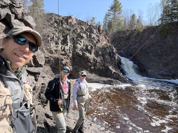 A man and two women near a waterfall 