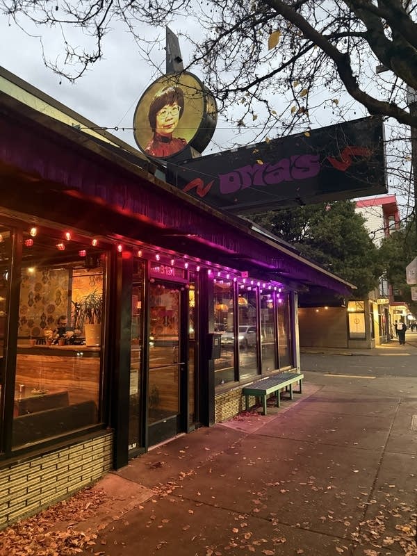 Exterior of a colorful restaurant. One sign says "Oma's" and another has an image of an older Asian woman with short hair.