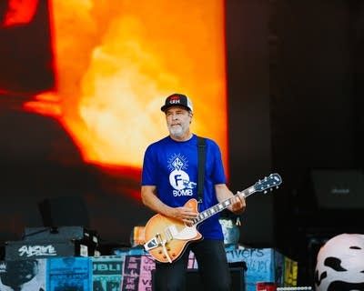 A musician plays guitar on a large outdoor stage