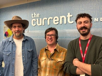 Three men stand together for a group portrait 