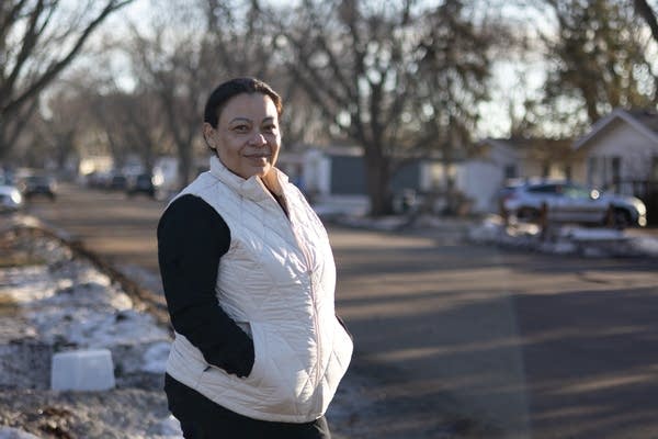 a woman stands with her hands in her coat pockets